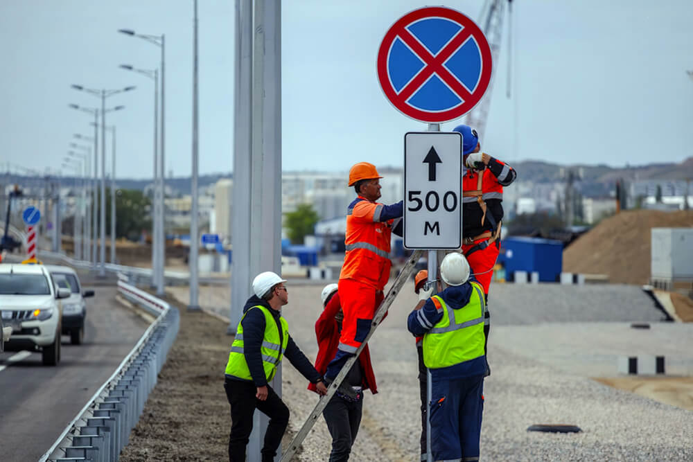 Рабочие устанавливают дорожный знак